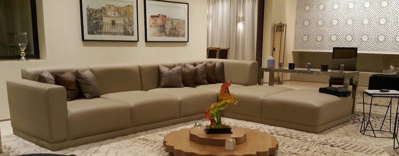 Séjour beige avec canapé d'angle, tapis berbère et tableaux encadrés
